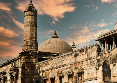 The magnificent sandstone dome and minaret of the Jama Masjid in Ahmedabad, set against a dramatic and colorful sunset sky