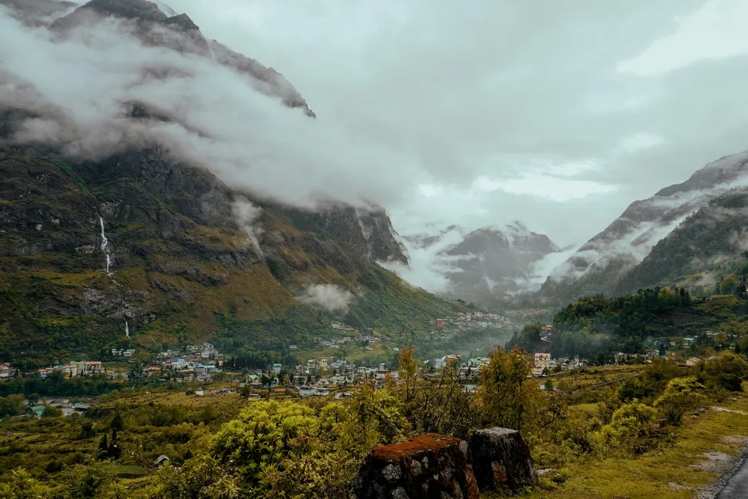 The remote village of Lachung nestled deep in a valley, surrounded by towering, cloud-shrouded Himalayan peaks in North Sikkim