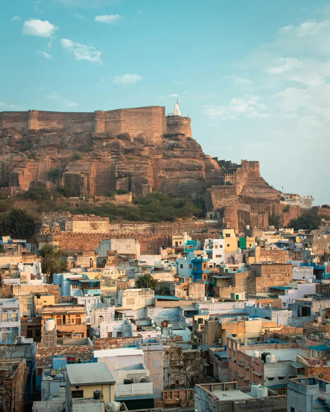 The majestic Mehrangarh Fort sits on a rocky cliff, overlooking the dense cluster of blue houses of the old city of Jodhpur