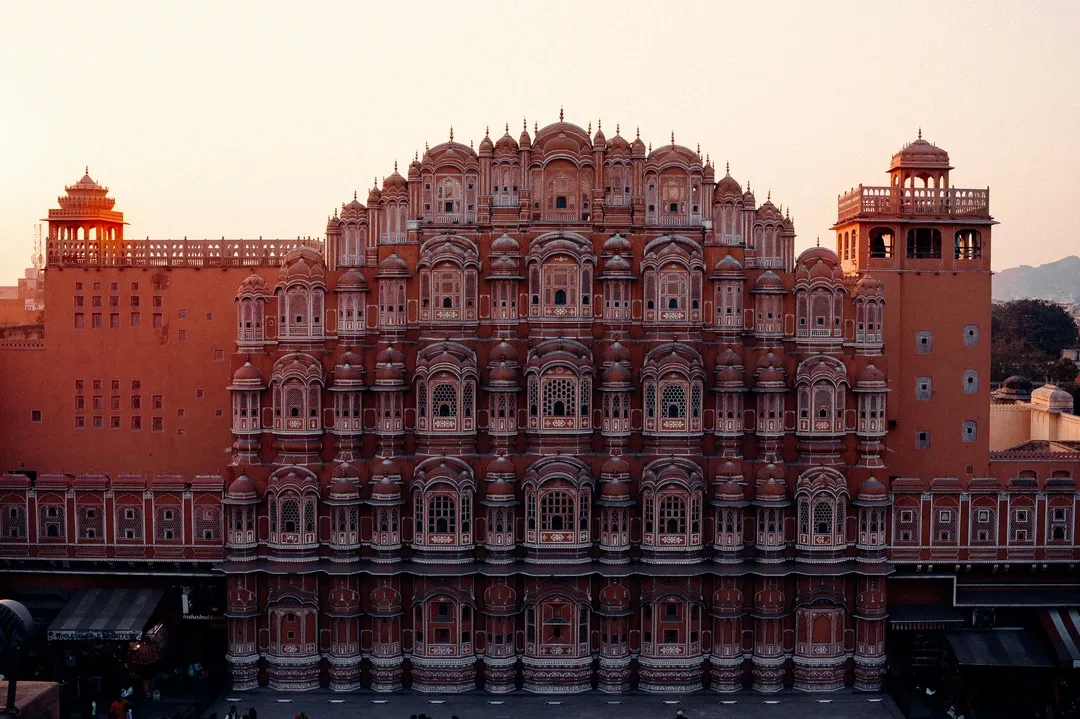 The iconic pink sandstone facade of the Hawa Mahal in Jaipur, with its 953 intricate windows glowing in the warm evening light