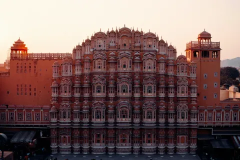 The iconic pink sandstone facade of the Hawa Mahal in Jaipur, with its 953 intricate windows glowing in the warm evening light