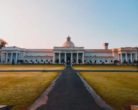 White domed museum building with broad lawn in front at golden hour