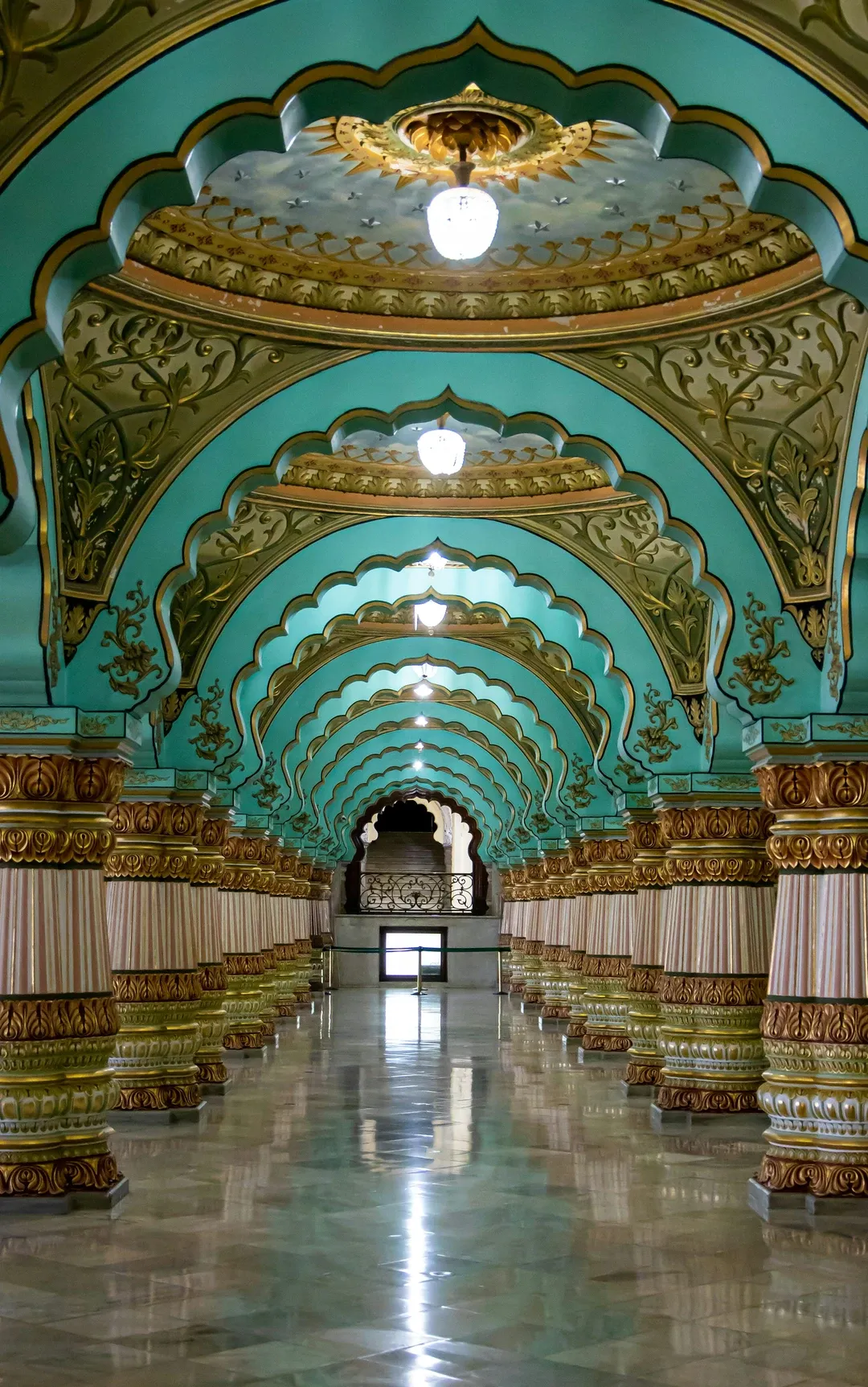 The magnificent corridor of the Mysore Palace, featuring its famous ornate pillars and turquoise scalloped arches