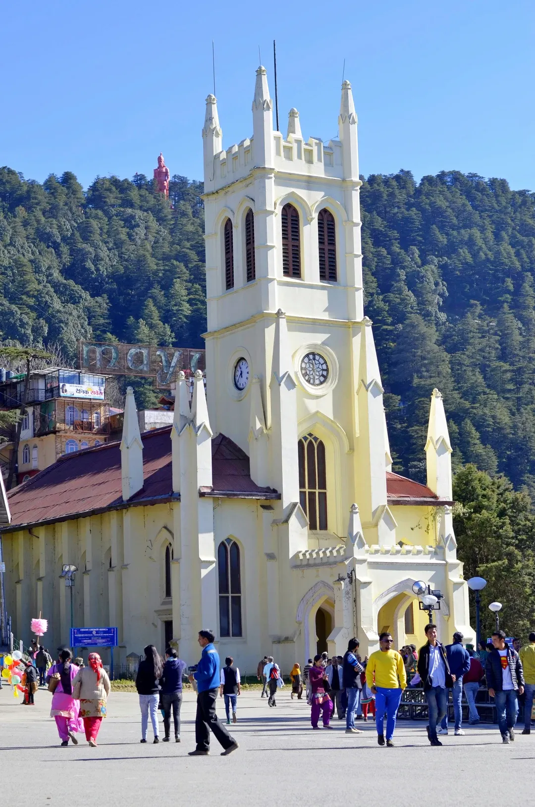 The historic Christ Church in Shimla, with tourists on The Ridge and the Jakhu Temple statue on the hill behind.