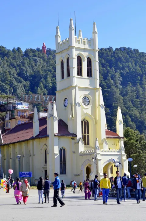 The historic Christ Church in Shimla, with tourists on The Ridge and the Jakhu Temple statue on the hill behind.