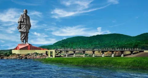 A scenic view of the Statue of Unity, the world's tallest statue, standing on the lush green banks of the Narmada River in Gujarat