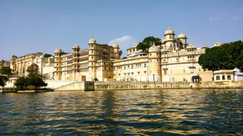 The sprawling Udaipur City Palace, a historic royal complex, seen from the shimmering waters of Lake Pichola in Rajasthan