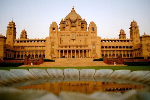 The grand, symmetrical facade of the Umaid Bhawan Palace in Jodhpur, a massive sandstone royal residence and luxury hotel