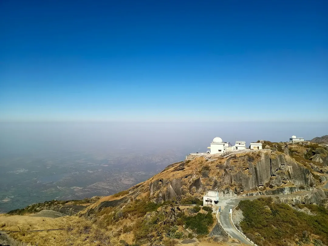 The white observatory domes on the summit of Guru Shikhar in Mount Abu, overlooking the vast, hazy plains of Rajasthan