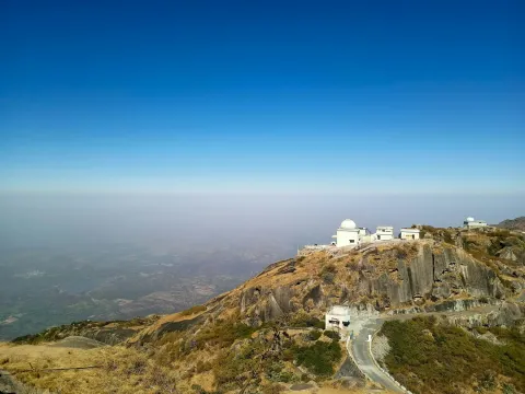 The white observatory domes on the summit of Guru Shikhar in Mount Abu, overlooking the vast, hazy plains of Rajasthan